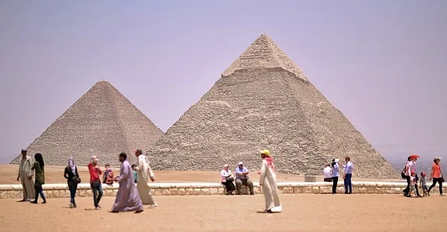 Grupo de turistas e camelo nas pirâmides de Guizé ilustrando grau de alavancagem financeira gaf