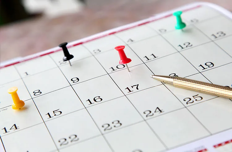 Calendário com alfinetes coloridos marcando cronograma e exigências do bloco k