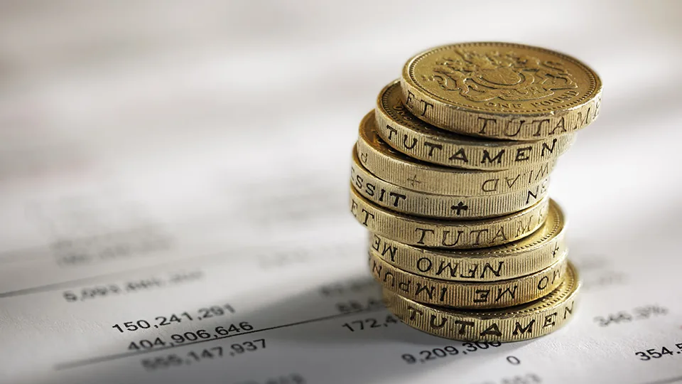 Pilha moedas britânicas sobre documento com números balanço patrimonial projetado
