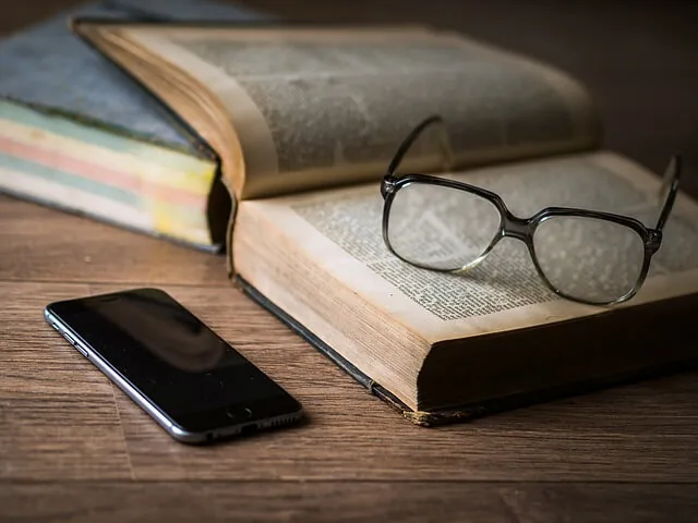 Óculos sobre livros representando educação continuada para certificado CFP