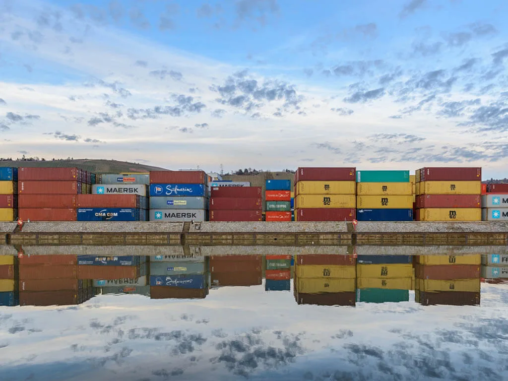 Contêineres em porto com reflexo demonstram a importância do ICMS em operações