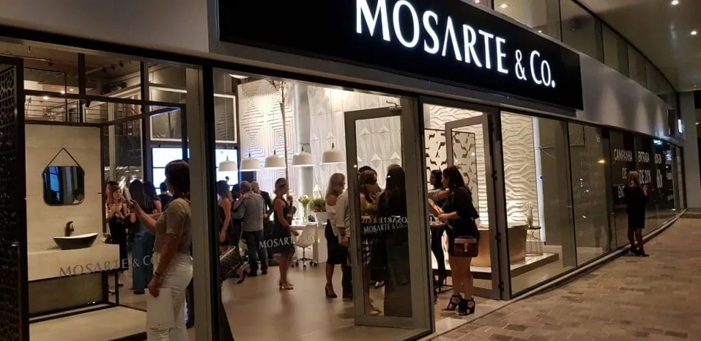 Interior iluminado da loja Mosarte & Co com clientes circulando entre produtos vitrines