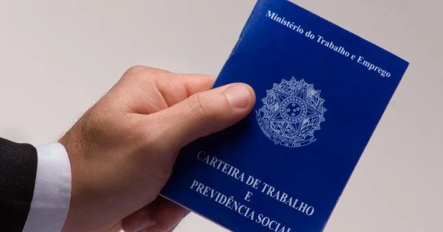 Mão de profissional segurando carteira de trabalho simbolizando custos com pessoal