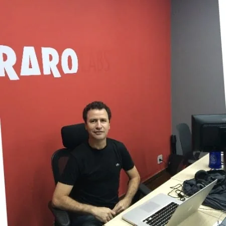 Ramon Setragni fundador da Raro Labs posando em escritório com parede vermelha