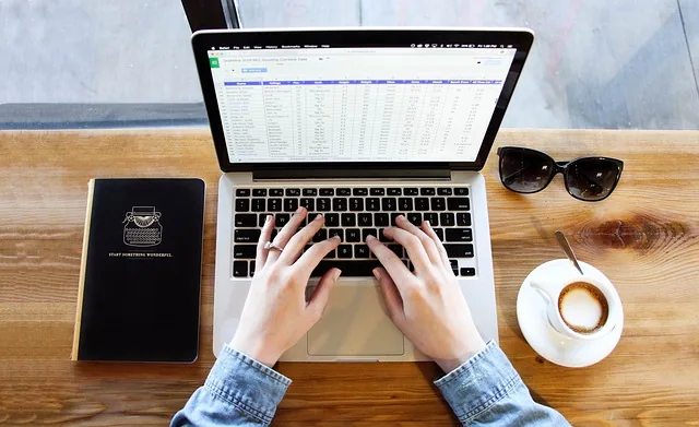 Profissional digitando laptop com documentos analisando receita bruta de vendas