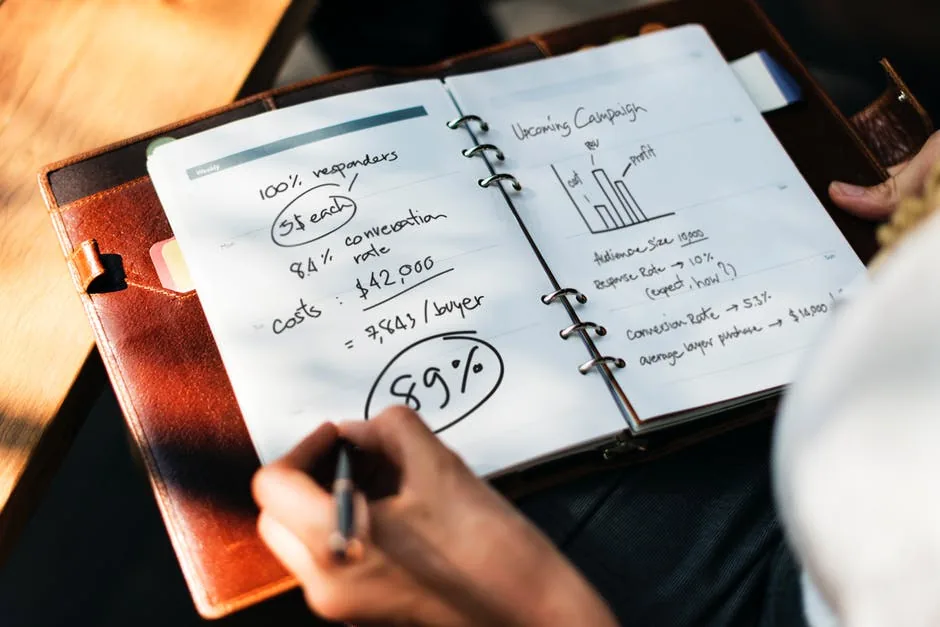 Mãos anotando caderno com gráficos esboçados para orçamento marketing planejado